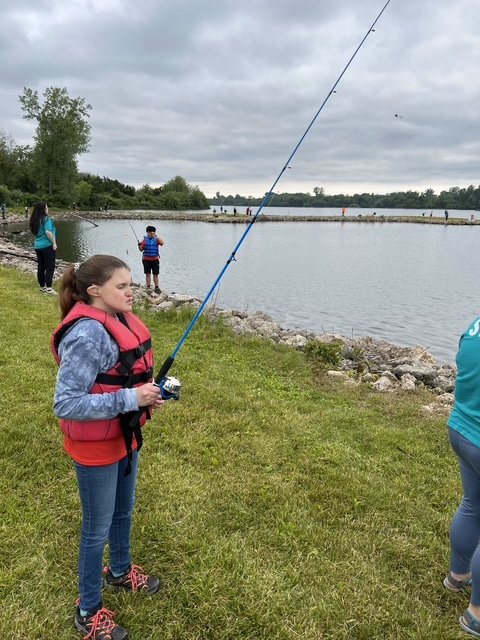 Volunteer helping an angler land a fish at Camp Courageous (gallery view)